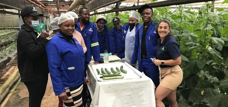 African Greeneurs participants and their trainer with freshly harvested cucumbers in a greenhouse